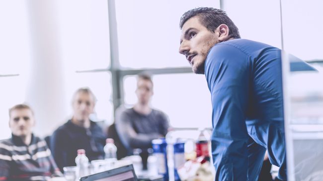 Geschäftsmann, der eine Präsentation im Büro gibt. Unternehmensleiter, der seinen Kollegen bei einem Meeting oder einer internen Unternehmensschulung eine Präsentation hält und seinen Mitarbeitern Geschäftspläne erklärt.