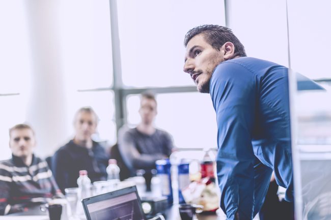 Geschäftsmann, der eine Präsentation im Büro gibt. Unternehmensleiter, der seinen Kollegen bei einem Meeting oder einer internen Unternehmensschulung eine Präsentation hält und seinen Mitarbeitern Geschäftspläne erklärt.