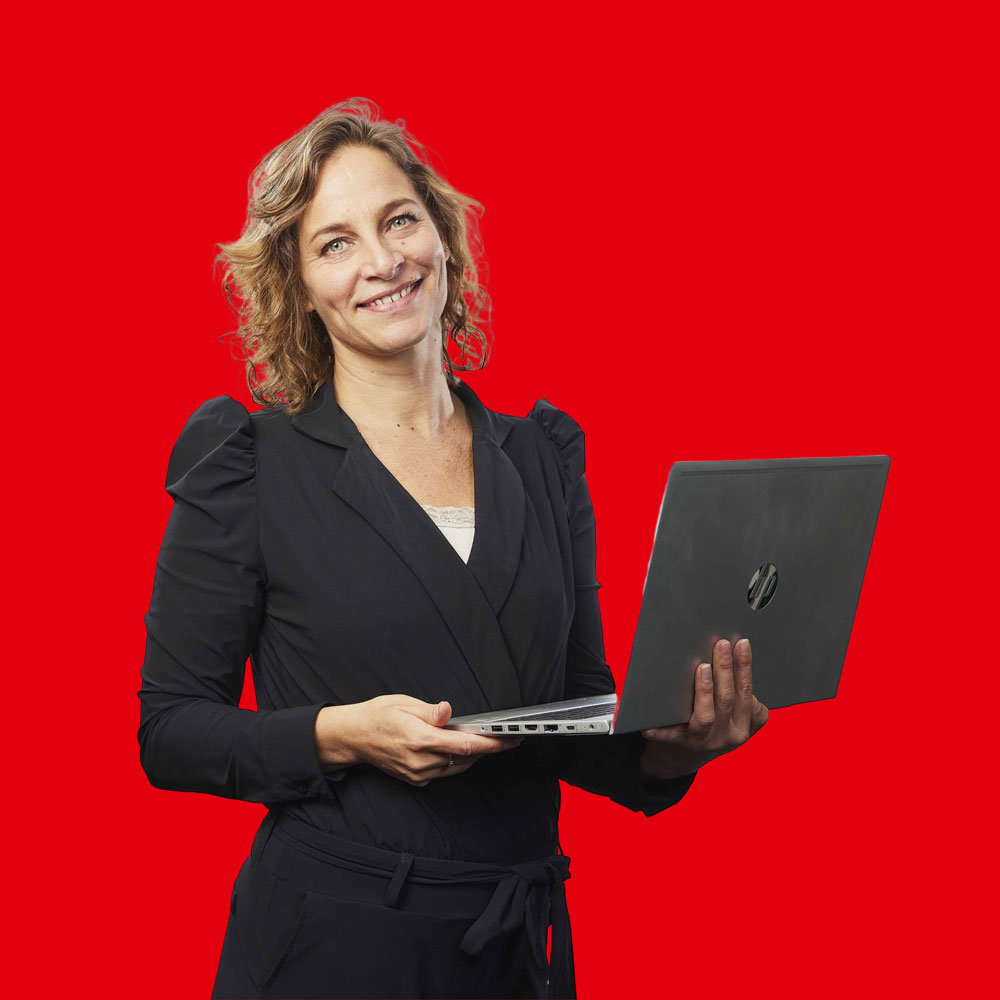 Dame mit blonden Haaren in einem schwarzen Overall mit einem Laptop